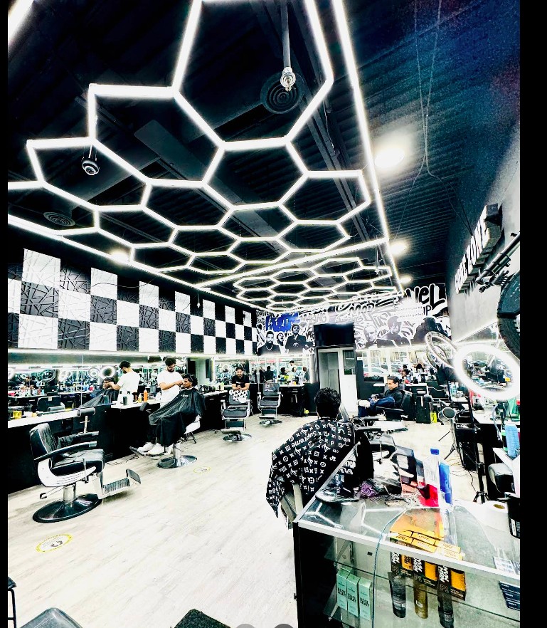 Inside Gore Zone Barber Shop — hex LED ceiling, checkerboard accent wall and a hand-painted mural of cultural icons on the back wall